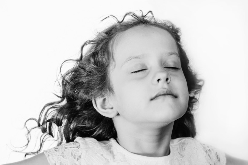 Little girl closed her eyes and breathes the fresh air. Black an